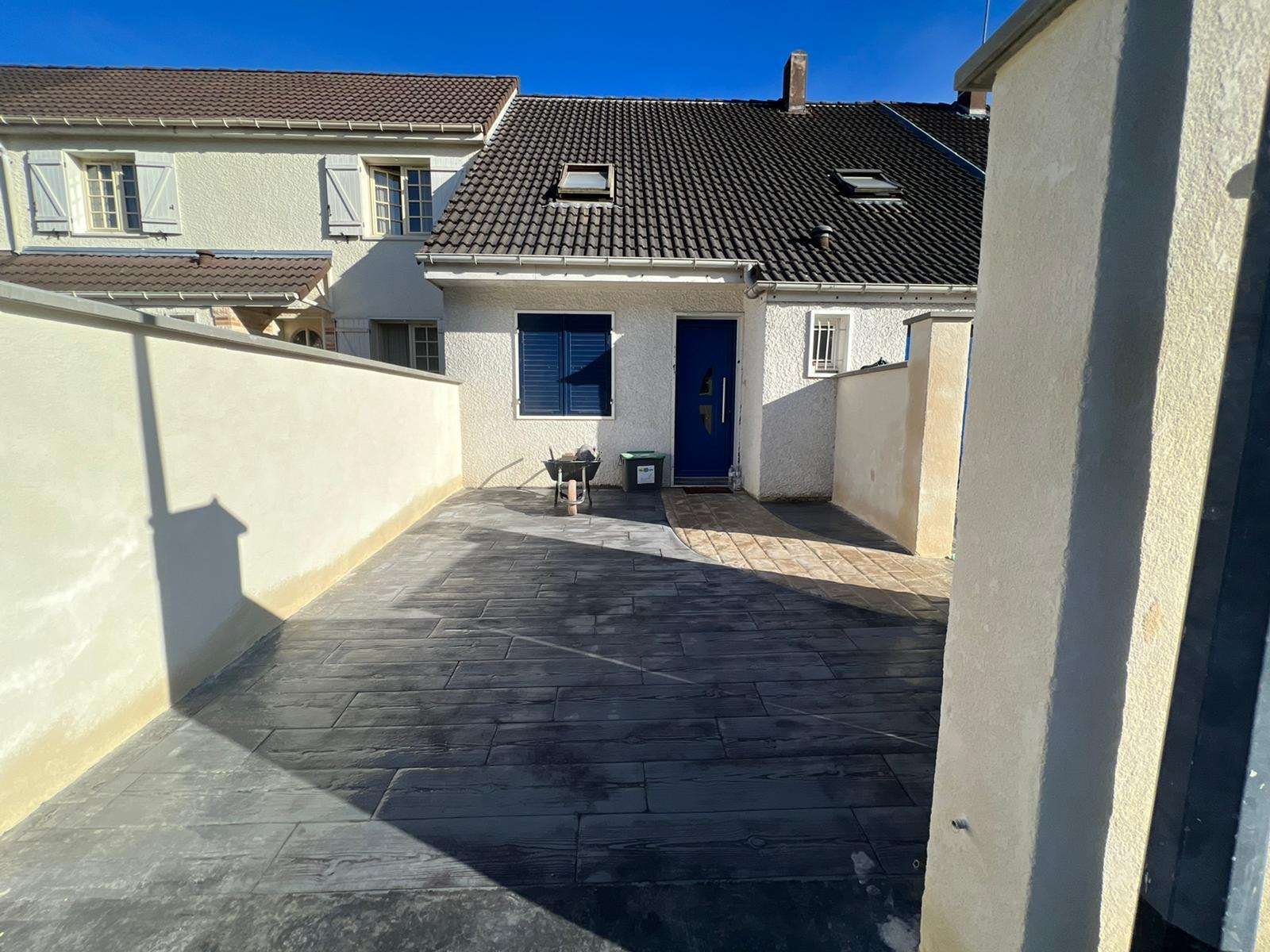 Terrasse en béton imprimé gris anthracite entre deux murs, devant une maison