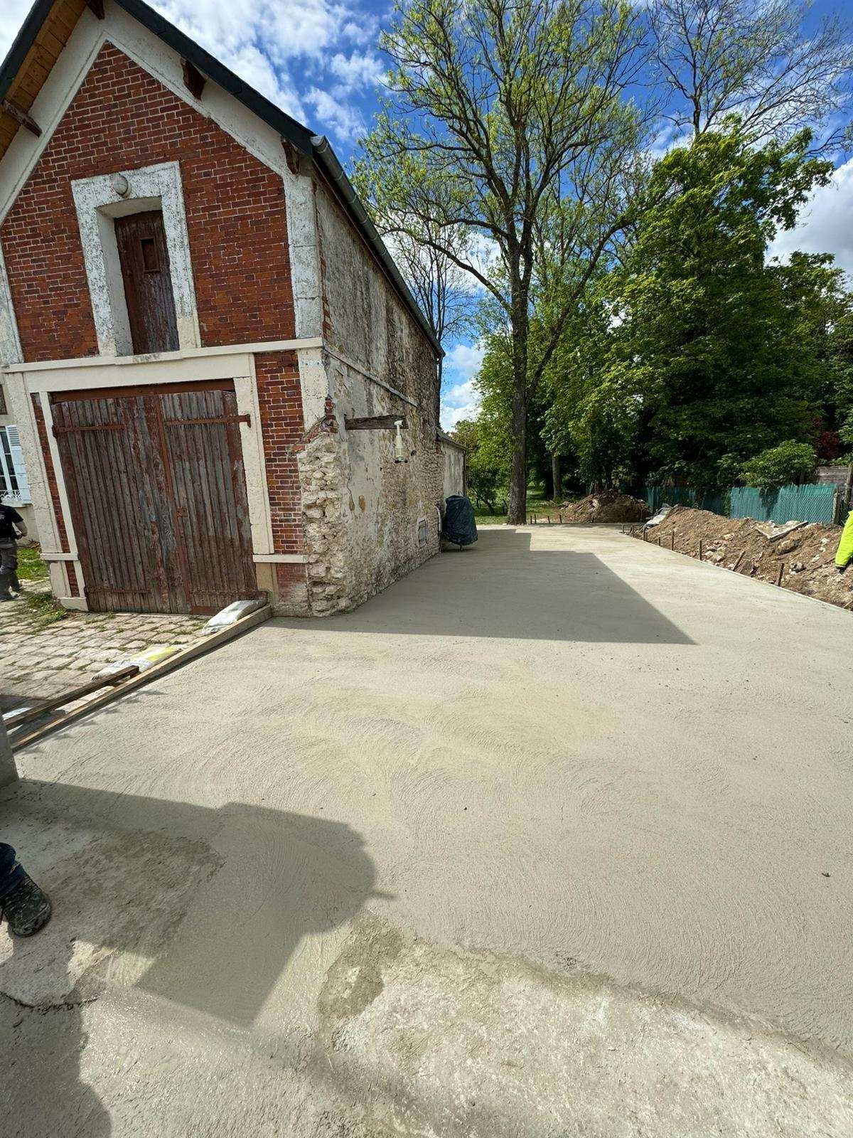 Dalle béton coulée devant une grange en brique