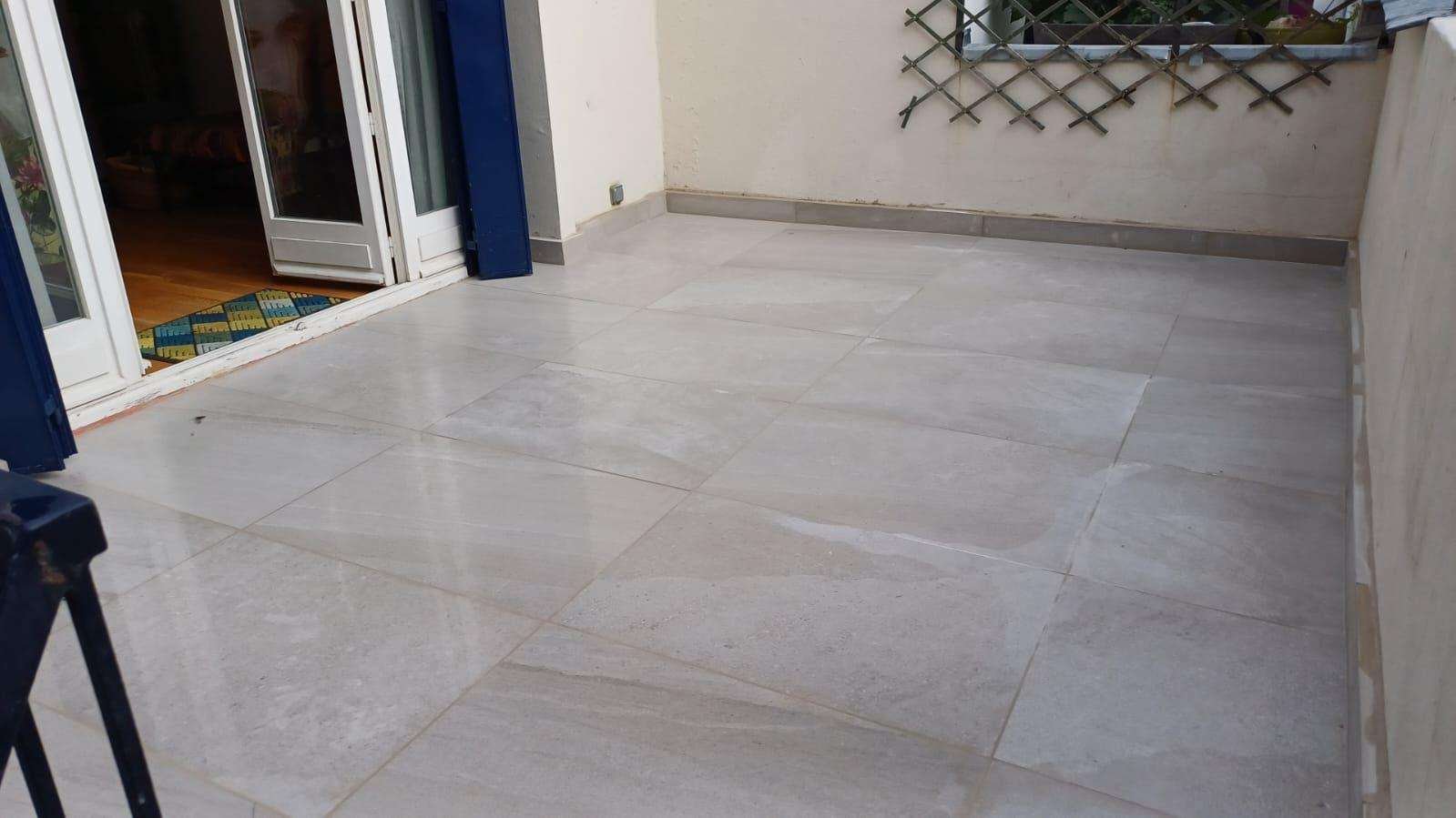 Terrasse carrelée en grand format clair au pied d’une façade